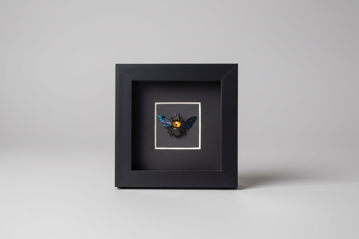 Small black framed artwork with a bee design on a gray background